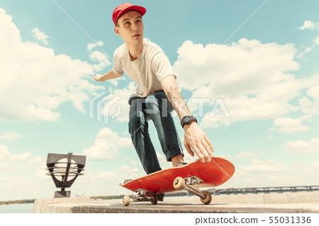 Skateboarder doing a trick at the city's street in sunny day Skateboarder doing a trick at the city's street in sunny day 55031336