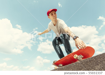 Skateboarder doing a trick at the city's street in sunny day Skateboarder doing a trick at the city's street in sunny day 55031337