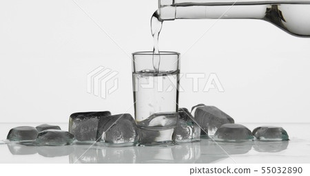 Pouring up shot of vodka from a bottle into glass. White background Pouring up shot of vodka from a bottle into glass. White background 55032890