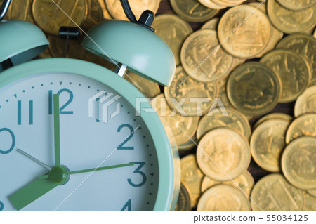 Alarm clock and coins stacks on working table in 55034125
