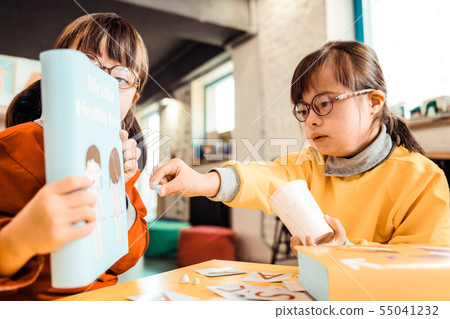 Curious kid with tied hair pointing on a bright cover of learning book 55041232