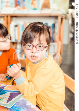 Dark-haired young girl with long bangs and eyeglasses wearing yellow sweater 55041421