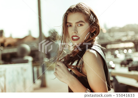 Resolute dark-haired girl with bright red lips staying in sun lights 55041633