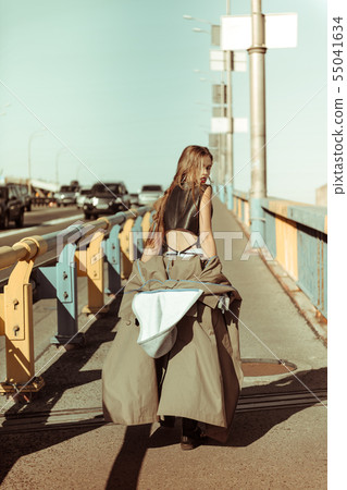 Sexy drastic long-haired woman taking off grey coat 55041634