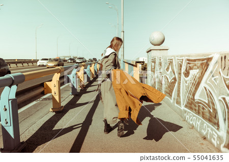 Active long-haired woman carrying her oversize jacket 55041635