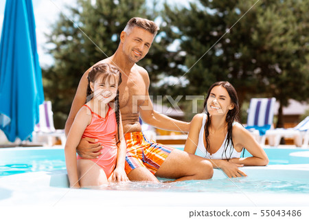 Girl wearing swimming suit swimming with parents Girl wearing swimming suit swimming with parents 55043486