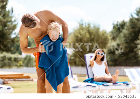 Son feeling happy after swimming while standing with towel 55043533