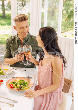 Dark-haired wife wearing pink dress drinking wine with husband 55043833