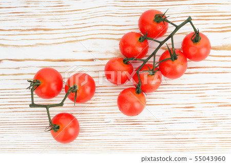 Ripe cherry tomatoes on a twig on a white woden 55043960