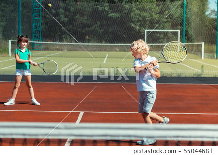 Brother hitting the tennis ball while playing with sister 55044681