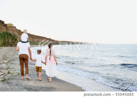 Family of four walking along the seashore. Parents 55045085