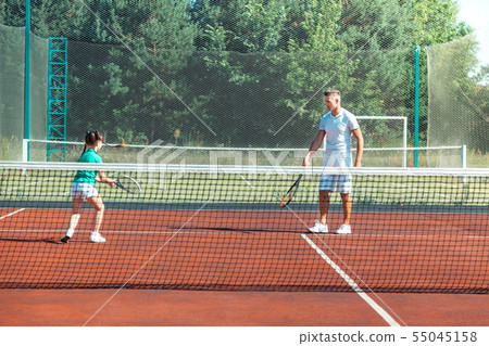 Dark-haired girl running while playing tennis with daddy Dark-haired girl running while playing tennis with daddy 55045158