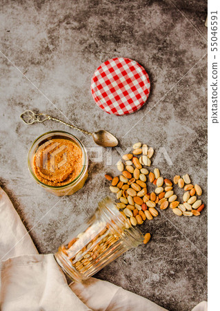 Jar and spoon of peanut butter and peanuts on dark Jar and spoon of peanut butter and peanuts on dark 55046591