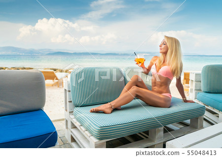 Woman holding Delicious classic iced aperol spritz cocktail with ice cubes on a hot tropical beach 55048413