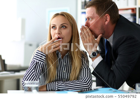Male clerk sharing some secret knowledge with female colleague Male clerk sharing some secret knowledge with female colleague 55049792