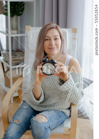Blonde young woman holding a black clock Blonde young woman holding a black clock 55052654