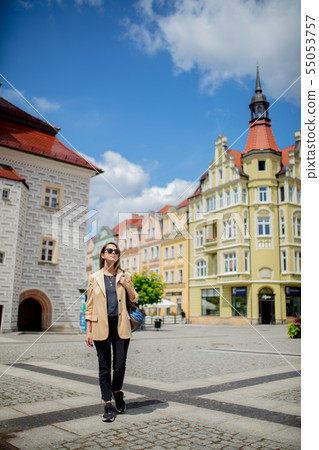woman in sunglasses and backpack in aged city center square. Poland 55053757