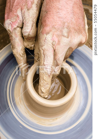 potter's hands mold pottery on a rotating wheel 55054479