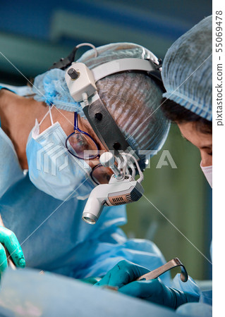 Surgeon and his assistant performing cosmetic surgery on nose in hospital operating room. Nose Surgeon and his assistant performing cosmetic surgery on nose in hospital operating room. Nose 55069478
