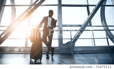 Confident Businessman Waiting for Flight in Airport Terminal Confident Businessman Waiting for Flight in Airport Terminal 55075511