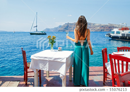 Young woman in a dress standing at a table Young woman in a dress standing at a table 55076213