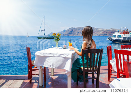 Young woman in a dress sitting at a table Young woman in a dress sitting at a table 55076214