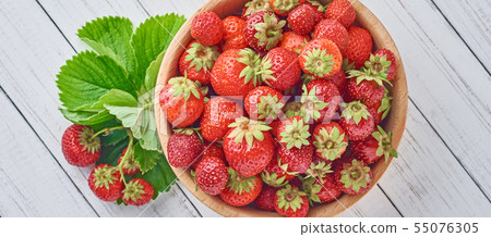 Fresh strawberries in wooden bowl and green leaves 55076305