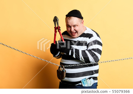 burglar with scissors in hands looking at the camera while standing behind the chain 55079366