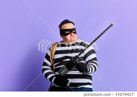 serious robber with a drilling machine makes illegal work. 55079427