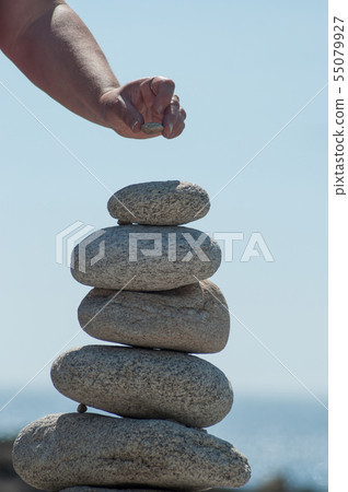 Closeup of woman putting pebble on stone balance  55079927