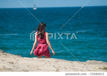 portrait of pretty girl wearing red dress walking 55080031