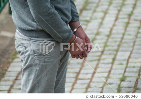 Closeup of hands of man handcuffed in the street 55080040