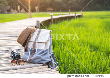 Backpack with hat and camera on bamboo path at 55099899