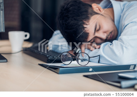 Tired asian businessman sleep on working desk Tired asian businessman sleep on working desk 55100004