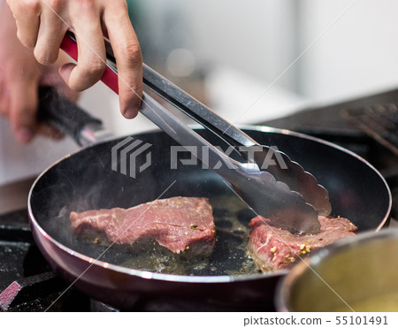 Fry the meat in a frying pan. Chef preparing and Fry the meat in a frying pan. Chef preparing and 55101491