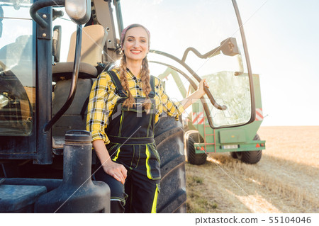 Farmer woman standing in front of tractor on wheat field Farmer woman standing in front of tractor on wheat field 55104046