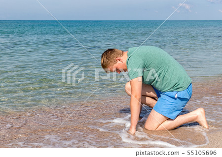Young man in a t-shirt on the seashore and looks Young man in a t-shirt on the seashore and looks 55105696