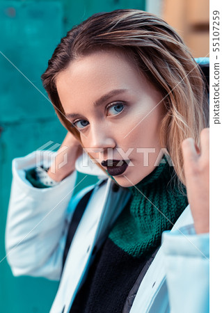 Blue-eyed fashion model with dark lipstick posing outside 55107259
