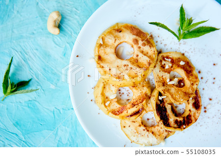 Grilled apples with cinamon on white plate on blue background. Grilled apples with cinamon on white plate on blue background. 55108035