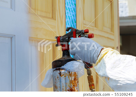 Hand with spray gun painting wooden door Hand with spray gun painting wooden door 55109245