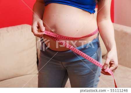 Pregnant woman measuring her belly close up Pregnant woman measuring her belly close up 55111246