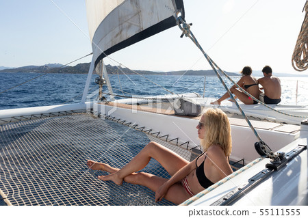 Beautiful woman relaxing on a summer sailing cruise, lying and sunbathing in hammock of luxury 55111555