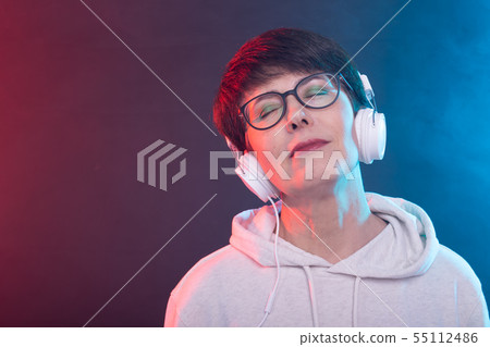 Hobby and leisure concept - Middle-aged woman listening music on blue background. 55112486