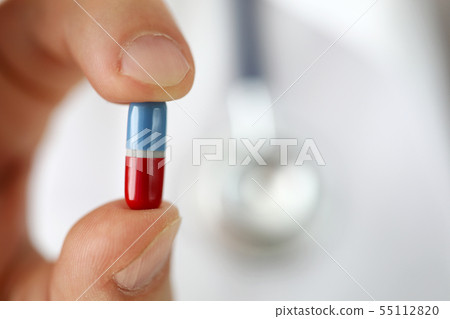GP holding in arm little pill offering it to patient close-up 55112820