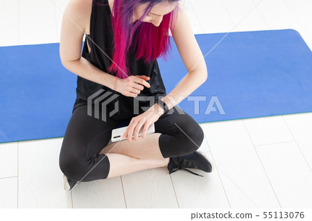 Unidentified girl with purple hair is counting burned calories using an app on her smartphone while Unidentified girl with purple hair is counting burned calories using an app on her smartphone while 55113076