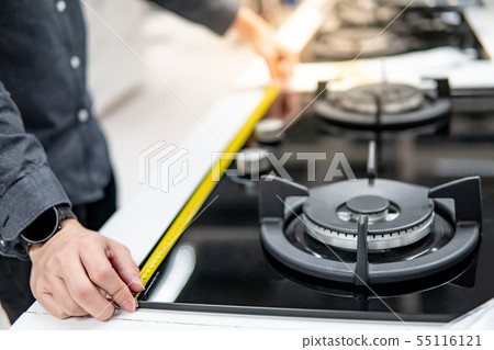 Male hand using tape measure on gas stove Male hand using tape measure on gas stove 55116121