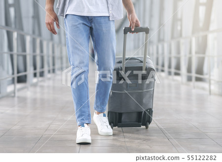 Man walking with luggage at airport corridor Man walking with luggage at airport corridor 55122282
