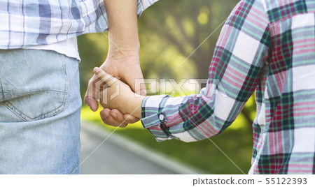 Father holds daughter by the hand while walking Father holds daughter by the hand while walking 55122393
