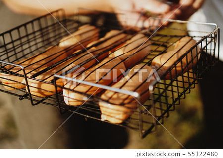 Delicious grilled sausages resting on the iron grid of a portable barbecue 55122480