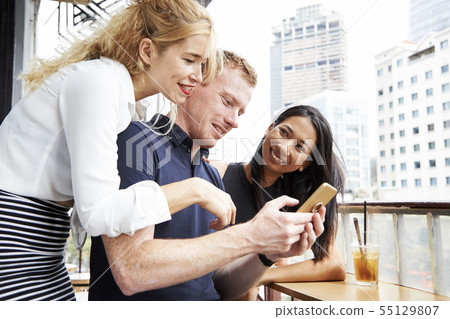Friends looking at photos in smartphone Friends looking at photos in smartphone 55129807